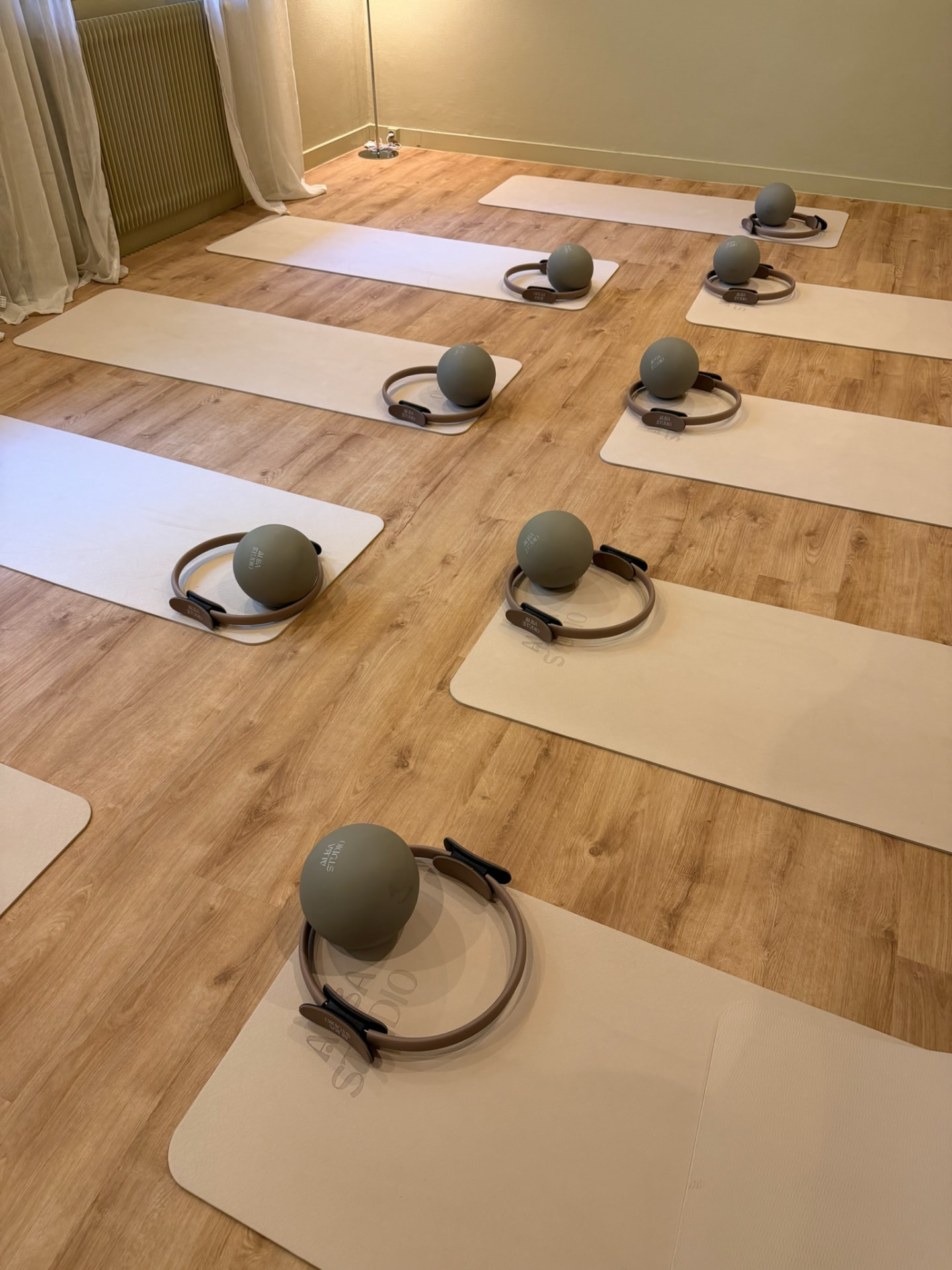 Tapis de Pilates Mat ALBA STUDIO alignés sur parquet, anneaux et balles d'exercice